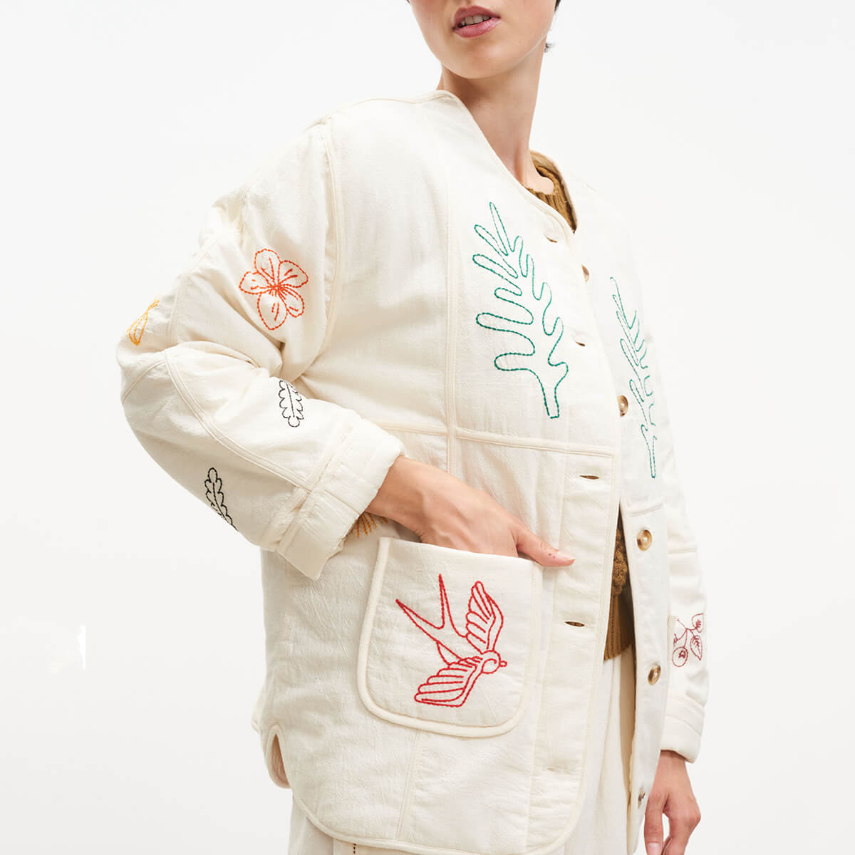 White embroidered outfit with floral and bird designs on a white background