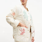 White embroidered outfit with floral and bird designs on a white background